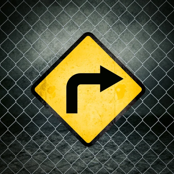 Señal de advertencia amarilla Grunge de dirección correcta en la valla de enlace de cadena — Foto de Stock