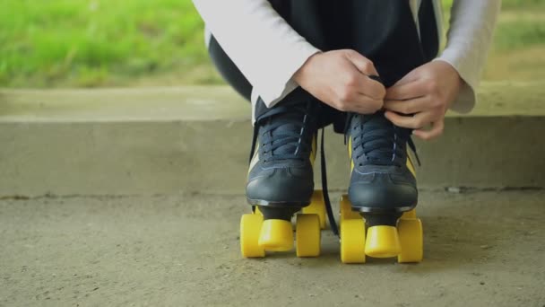 Vrouw banden veters op Vintage Retro Quad rolschaatsen, zittend op betonnen blok in stedelijke omgeving — Stockvideo