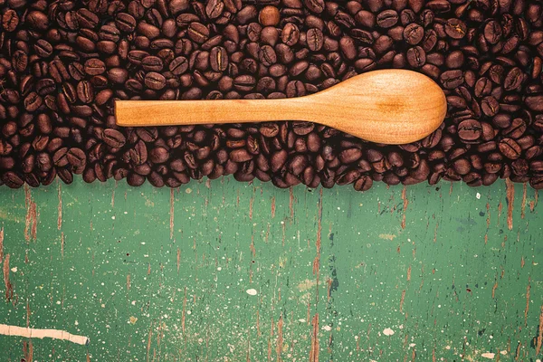 Chicchi di caffè torrefatto e cucchiaio su fondo in legno rustico — Foto Stock