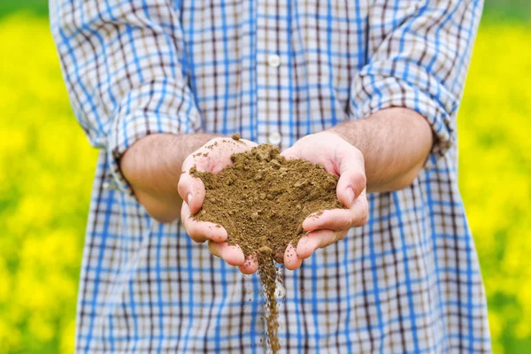 Фермер проверяет качество почвы на плодородных сельскохозяйственных землях — стоковое фото