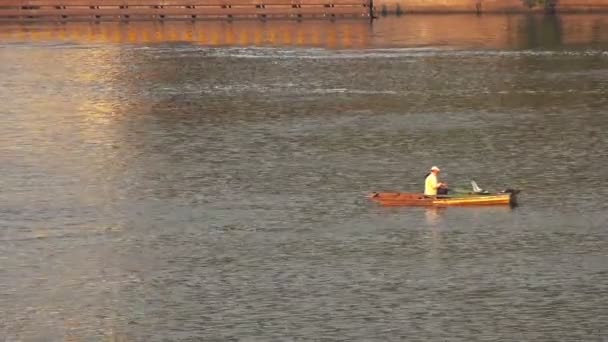 Человек рыбачит со своей лодки на реке Прага Влтава — стоковое видео