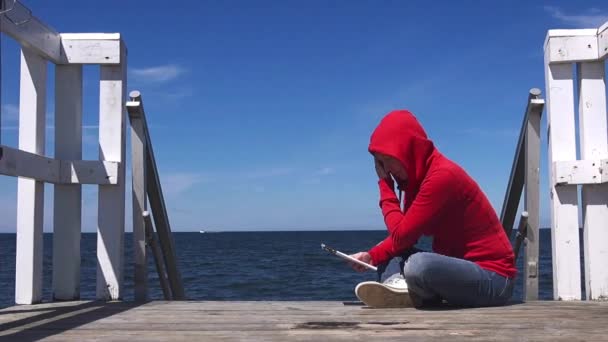 Mujer sola en camisa roja leyendo en Pier — Vídeos de Stock