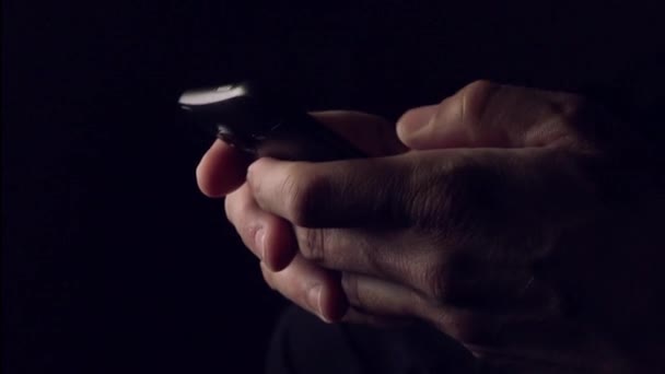 Человек, отправляющий смс-сообщения в темной комнате — стоковое видео
