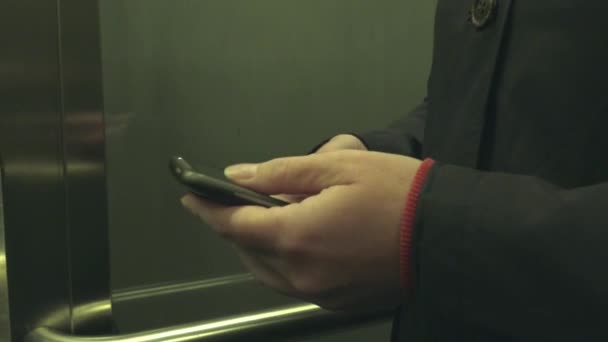 Woman sending SMS text message in elevator — Stock Video