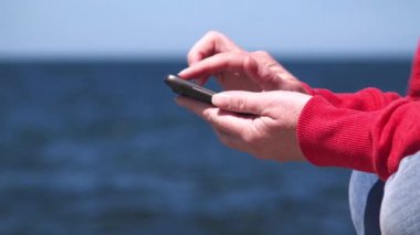 Okyanus iskelede mobil akıllı telefon kullanarak eller