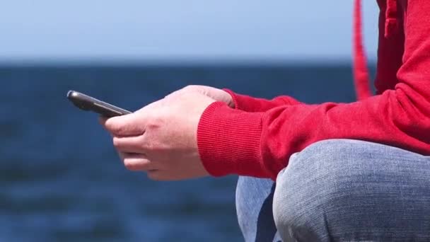 Hembra manos utilizando el teléfono inteligente móvil en el muelle del océano — Vídeos de Stock