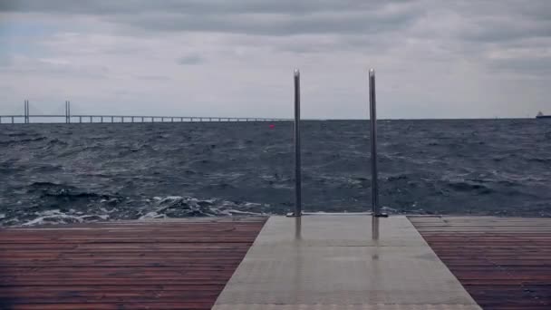 Waves splashing wooden ocean pier on stormy day — Stock Video