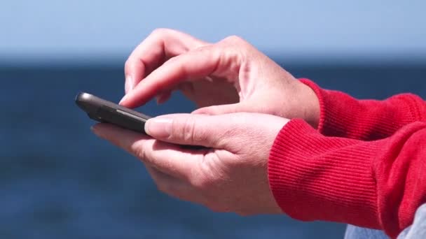 Ženské ruce pomocí chytrý mobilní telefon v oceánu pier — Stock video