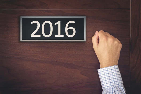 Бизнесмен стучится в новогоднюю дверь 2016 года — стоковое фото