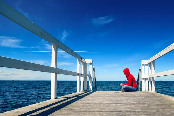 Kvinnan textning på Smart telefon på Ocean Pier — Stockfoto