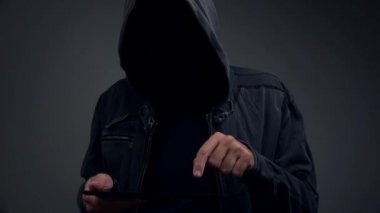Tanınmayan kukuletalı kişi dijital tablet bilgisayar ile