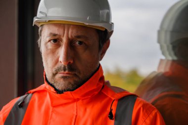 İnşaat alanındaki kameraya bakan kendine güvenen inşaat mühendisi, mühendislikteki profesyonelliğin ve sorumluluğun sembolü. Seçici odak.