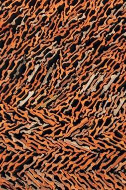 Eski terracotta kiremitlerinin yakın çekim deseni sıcak toprak tonlarında soyut geometrik bir doku oluşturuyor. Dikey resim.