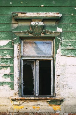 Çürük yeşil boyalı, kırık camlı, yıpranmış eski bir binanın ön cephesi. Dikey resim.