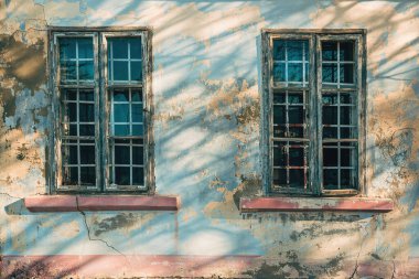 Kırık ve gölgeli iki eski ahşap pencere kentsel çürüme arka planında