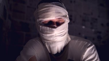 Beyaz bandajlı gizemli figür loş odaya sarılı, seçici odak