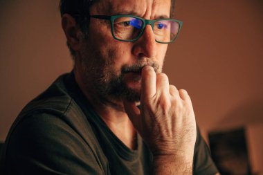 Ciddi bir endişe, düşünceli orta yaşlı, eli çenesinde, seçici odaklı bir adam.