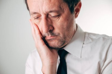 Beyaz gömlekli ve siyah kravatlı bir iş adamı, gözleri nazikçe kapalı ve kafası derin bir yorgunluk içinde elinin üzerinde dinleniyor. Seçici odak.
