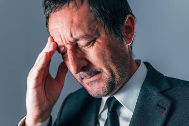 Stresli işadamı tapınağı acıyla ovuyor, seçici odaklanıyor