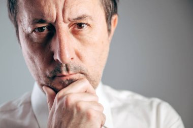 Ciddi bir işadamı eli çenesinde derin bir düşünce portresi, seçici bir odak noktası