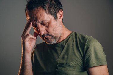 Endişeli yüz ifadesi olan, eli alnında, seçici odaklı bir adam.