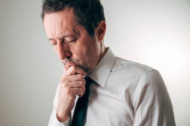 Çenesinde elleri olan düşünceli bir iş adamı. Aşağıya bakıyor, seçici odaklanıyor..