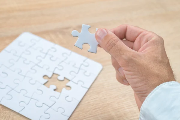 Pengusaha tangan menempatkan bagian yang hilang ke dalam teka-teki jigsaw — Stok Foto