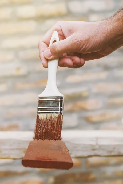 Hombre pintando piquetes de madera para cerca de hachís — Foto de Stock