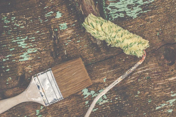 Old paintbrush and paint roller on rustic wooden board — Stock Photo, Image