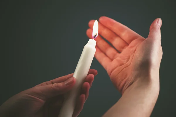 Frauenhände mit brennender Kerze im Dunkeln — Stockfoto