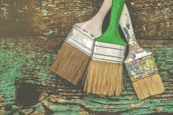 Three used paintbrushes on rustic wooden board