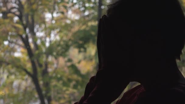 Silueta de solitaria mujer junto a la ventana — Vídeo de stock