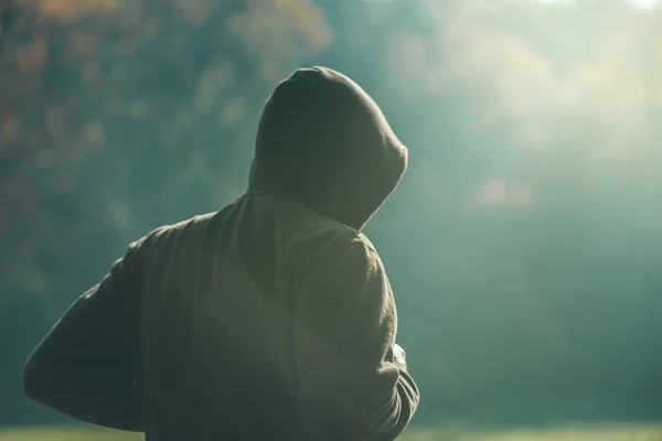 Hooded man jogging in the park in early autumn morning — Stock Photo, Image