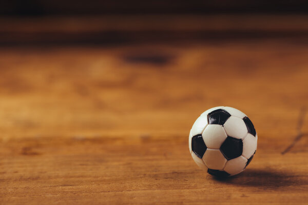 Миниатюрный пластиковый футбольный мяч на деревянном столе
