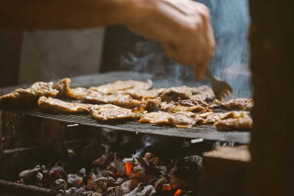 Hombre asar chuletas de carne de cerdo en la barbacoa — Foto de Stock