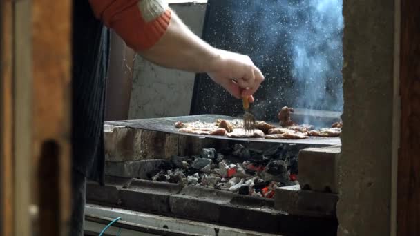 Чоловік смажить свиняче м'ясо на барбекю — стокове відео