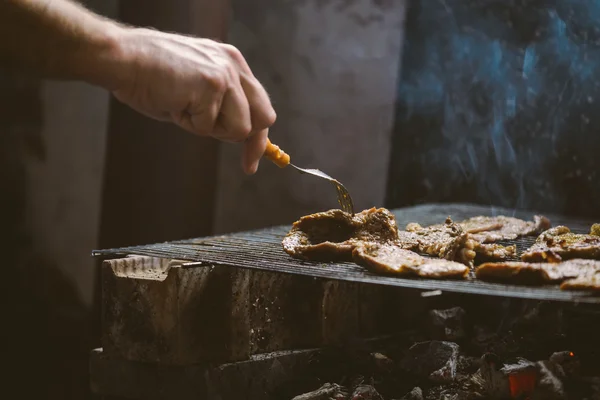 Hombre asar chuletas de carne de cerdo en la barbacoa — Foto de Stock