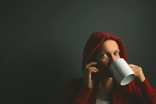 Linda mulher com capuz vermelho bebendo café e usando celular phon — Fotografia de Stock