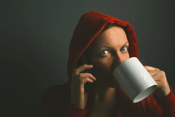 Linda mulher com capuz vermelho bebendo café e usando celular phon — Fotografia de Stock