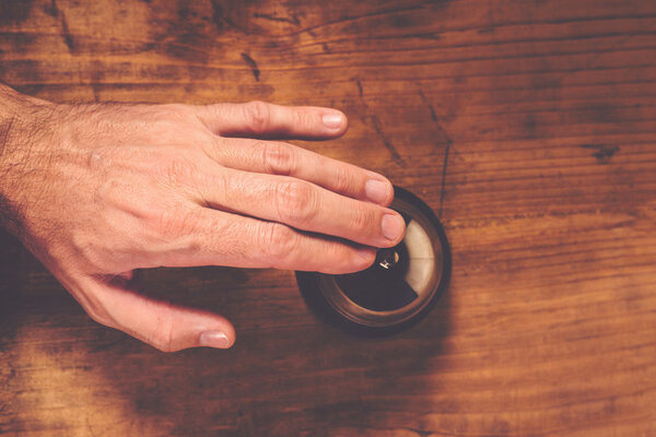 Мужчина звонит в гостиничный звонок на стойке регистрации
