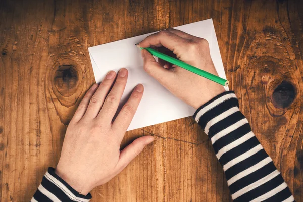 Mujer escribiendo dirección del remitente en el sobre de correo — Foto de Stock