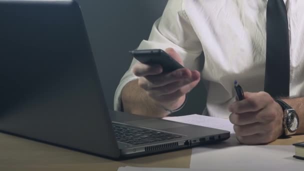 Empresario escribiendo notas del plan de proyecto y utilizando el teléfono inteligente móvil — Vídeos de Stock