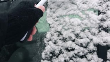Adam araba pencerelerden kar süpürme