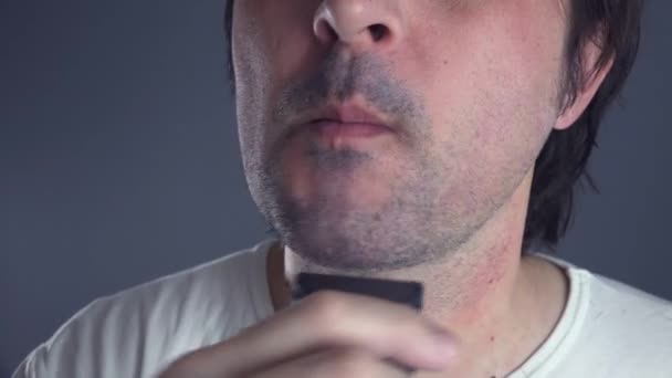 Hombre recortando su vello facial con afeitadora eléctrica — Vídeo de stock