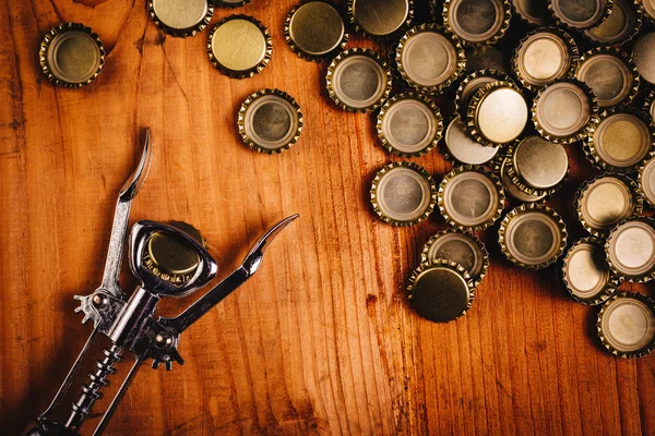 Klassischer Flaschenöffner und Stapel Bierflaschenverschlüsse — Stockfoto