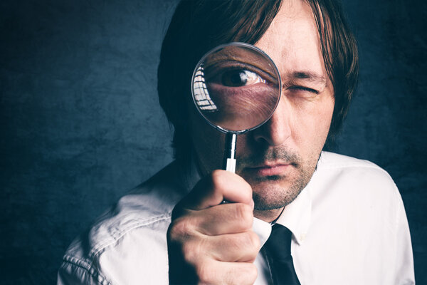 Businessman with magnifying glass, tax inspector doing financial