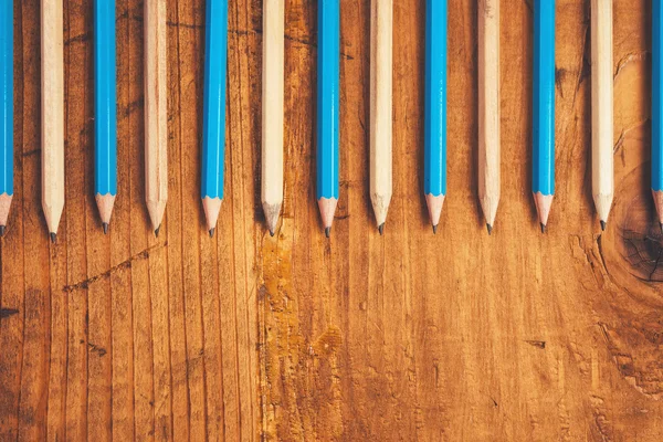 Blue and brown lined up pencils on rustic wooden table — Stock Photo, Image