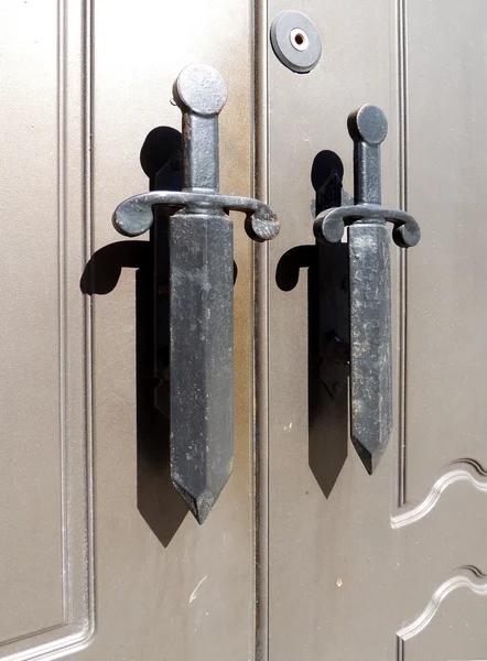 Фрагмент металлических дверей с ручками в виде кинжалов — стоковое фото