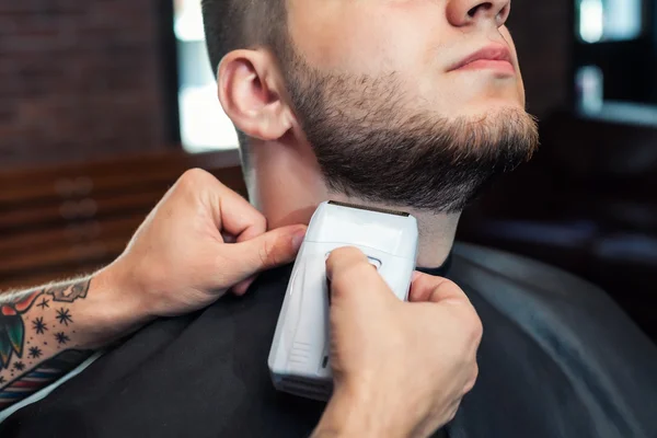 Young man having beard shaven