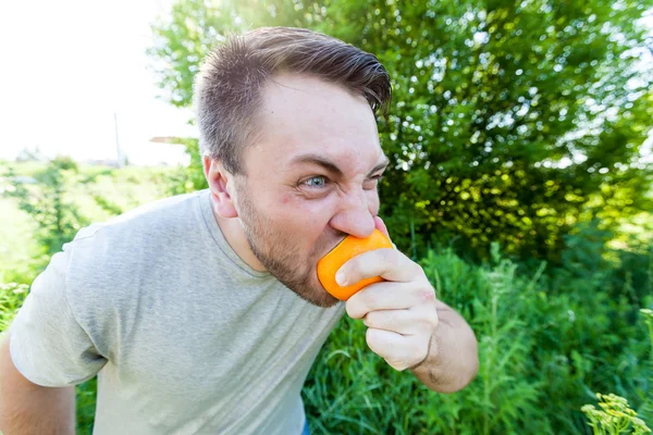 Homem comendo laranja ao ar livre — Fotografia de Stock